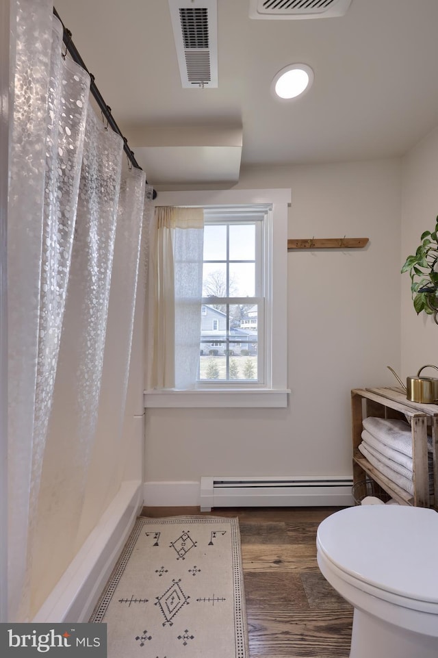 full bath featuring visible vents, toilet, wood finished floors, curtained shower, and a baseboard heating unit