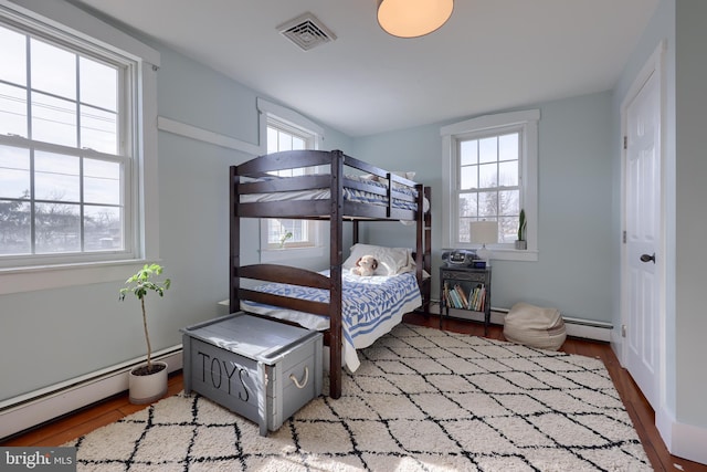 bedroom featuring a baseboard radiator, visible vents, and wood finished floors