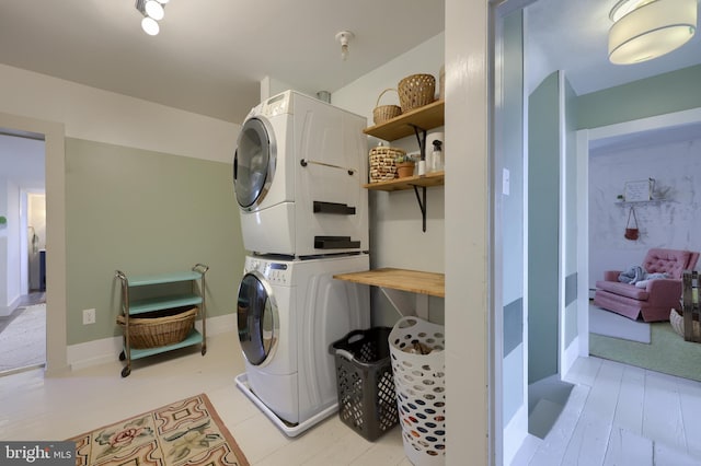 laundry room featuring laundry area, baseboards, and stacked washing maching and dryer