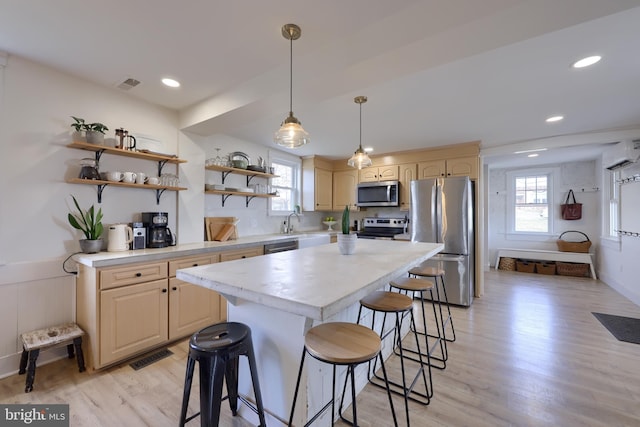 kitchen featuring light countertops, visible vents, appliances with stainless steel finishes, plenty of natural light, and a kitchen bar