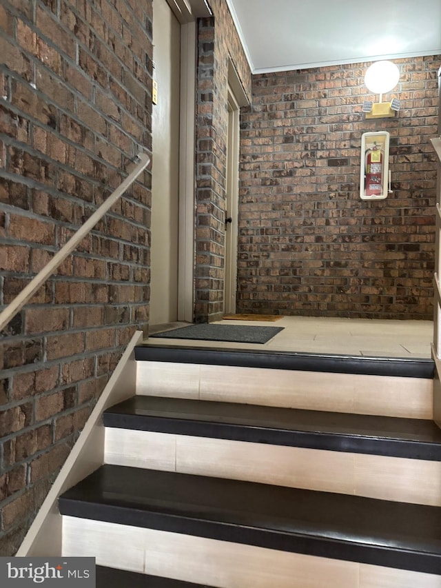 staircase featuring brick wall