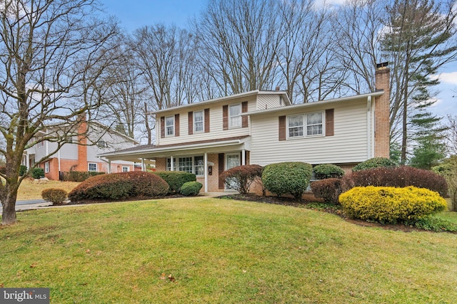 view of front of home featuring brick siding, a chimney, and a front yard