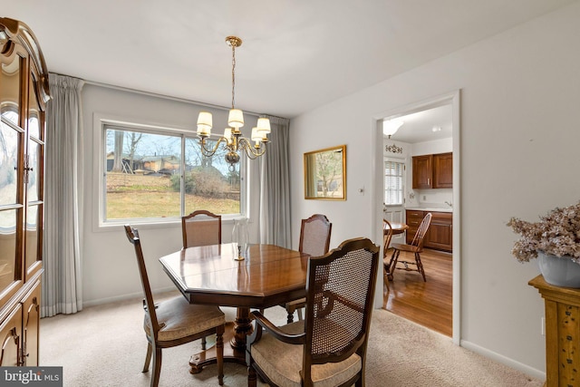 dining space featuring baseboards, an inviting chandelier, and light colored carpet