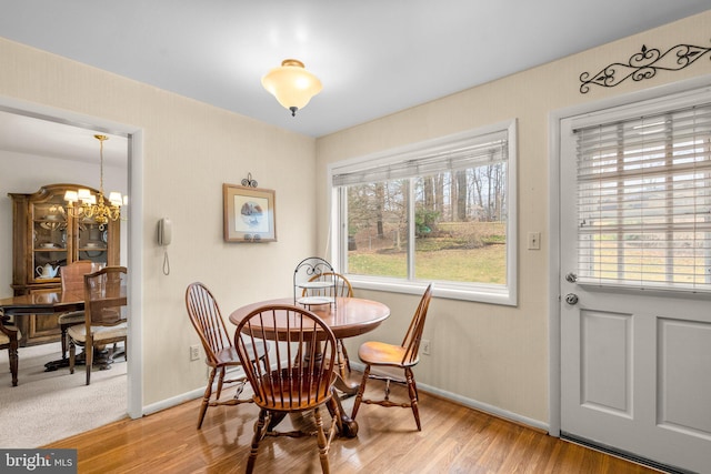 dining room featuring baseboards, light wood finished floors, and an inviting chandelier