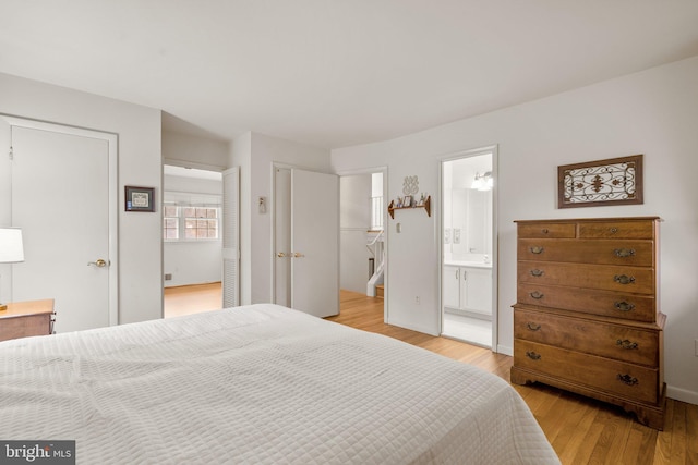 bedroom with light wood-type flooring, ensuite bath, and baseboards