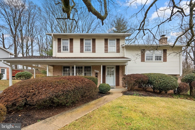 split level home featuring a chimney, a front lawn, a carport, and brick siding