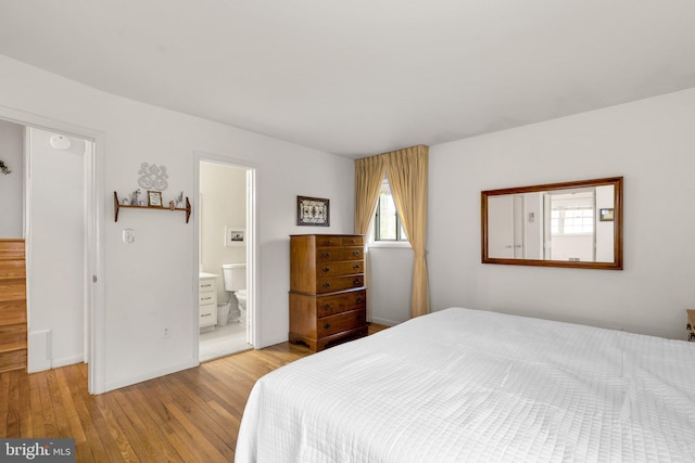 bedroom featuring ensuite bath, baseboards, and hardwood / wood-style floors