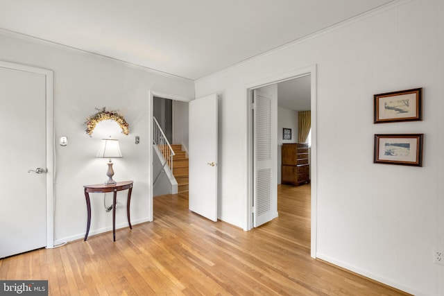 unfurnished room with ornamental molding, light wood finished floors, stairway, and baseboards