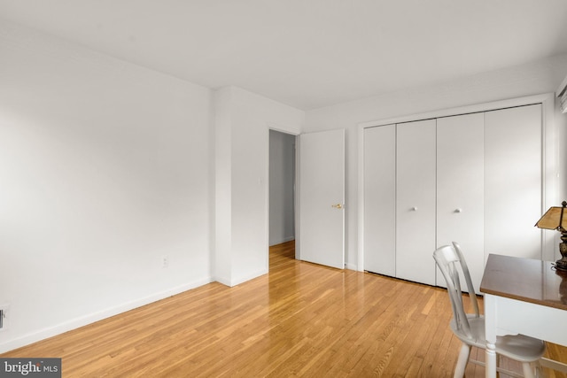 unfurnished bedroom featuring light wood-type flooring, a closet, and baseboards