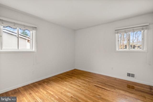 unfurnished room with light wood-type flooring, plenty of natural light, visible vents, and baseboards