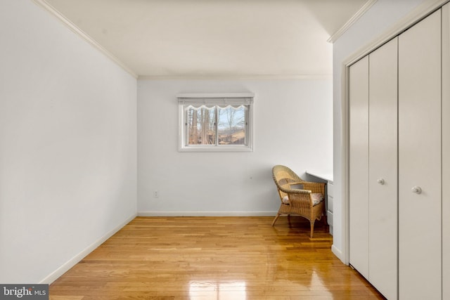 living area with baseboards, light wood-style flooring, and crown molding