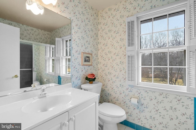 full bath featuring toilet, wallpapered walls, a shower stall, and vanity