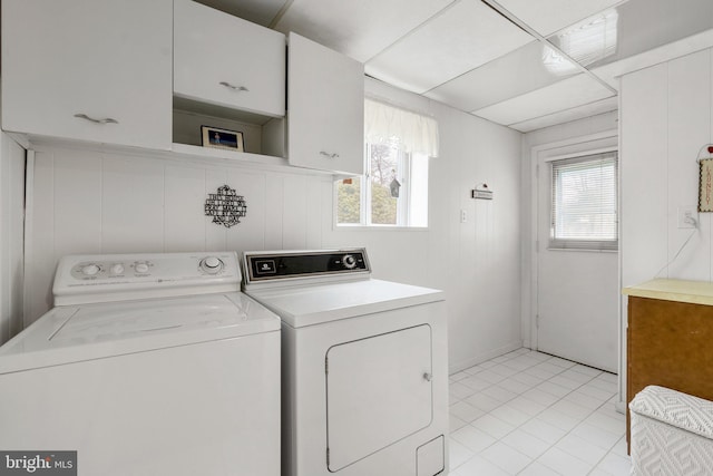 laundry room with light tile patterned floors, separate washer and dryer, cabinet space, and a healthy amount of sunlight