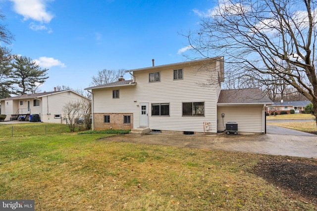 rear view of house with central air condition unit, fence, a lawn, a chimney, and a patio area