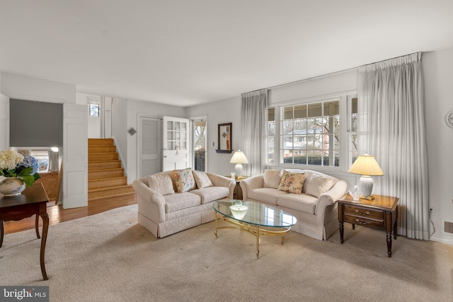 carpeted living room with a healthy amount of sunlight and stairway