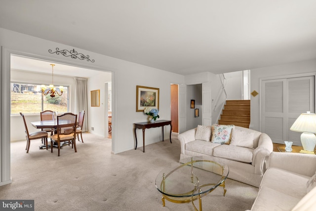 living room with light colored carpet, stairway, and an inviting chandelier