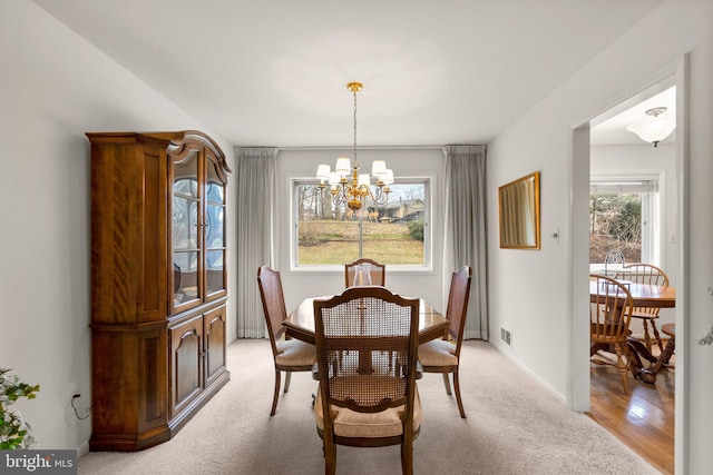 dining area with an inviting chandelier, visible vents, baseboards, and light colored carpet