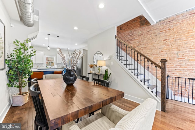 dining room with stairway, light wood-style flooring, and baseboards