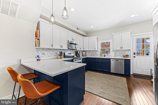 kitchen with stainless steel appliances, visible vents, backsplash, white cabinets, and a sink