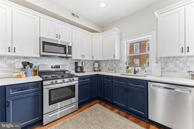 kitchen featuring blue cabinets, a sink, white cabinetry, visible vents, and appliances with stainless steel finishes