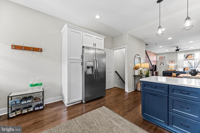 kitchen with white cabinets, stainless steel fridge with ice dispenser, dark wood-style flooring, blue cabinets, and pendant lighting