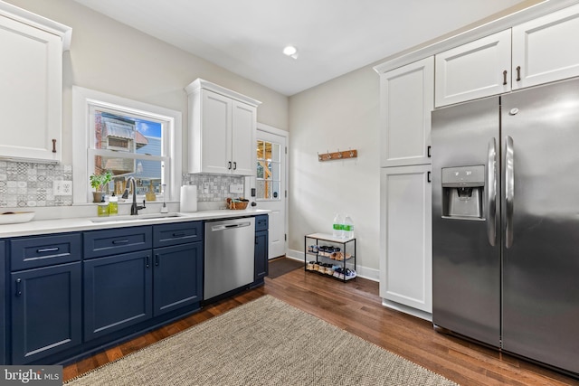 kitchen with blue cabinetry, stainless steel appliances, dark wood-type flooring, white cabinets, and a sink