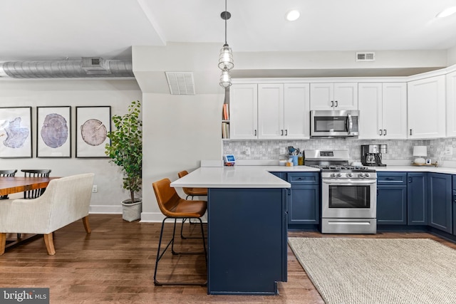 kitchen featuring visible vents, appliances with stainless steel finishes, a breakfast bar, light countertops, and blue cabinetry