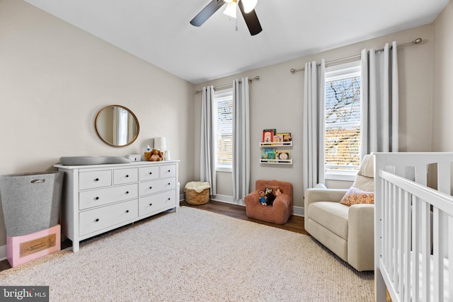 bedroom featuring ceiling fan, vaulted ceiling, wood finished floors, a crib, and baseboards