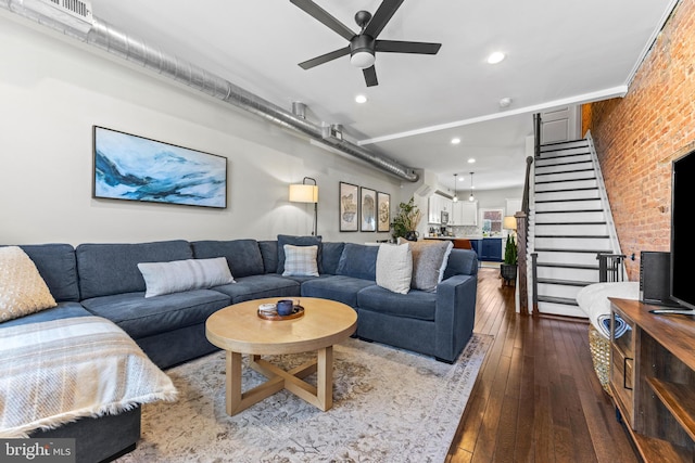 living room featuring visible vents, stairway, ceiling fan, brick wall, and hardwood / wood-style flooring