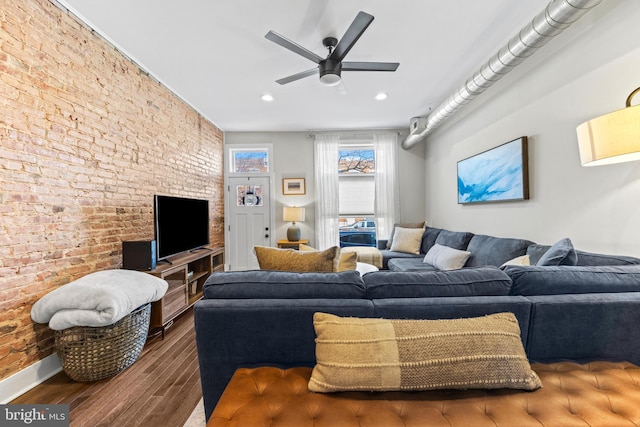 living area with baseboards, a ceiling fan, brick wall, wood finished floors, and recessed lighting