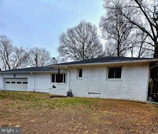 back of house with an attached garage, a chimney, and a yard