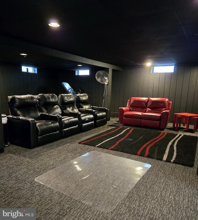 carpeted home theater room featuring wood walls