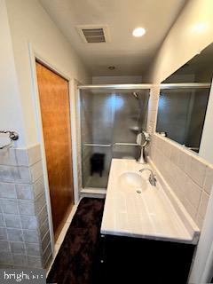 full bath featuring visible vents, a shower stall, vanity, and tile walls