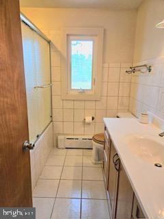 full bath with tile patterned floors, toilet, tile walls, baseboard heating, and vanity