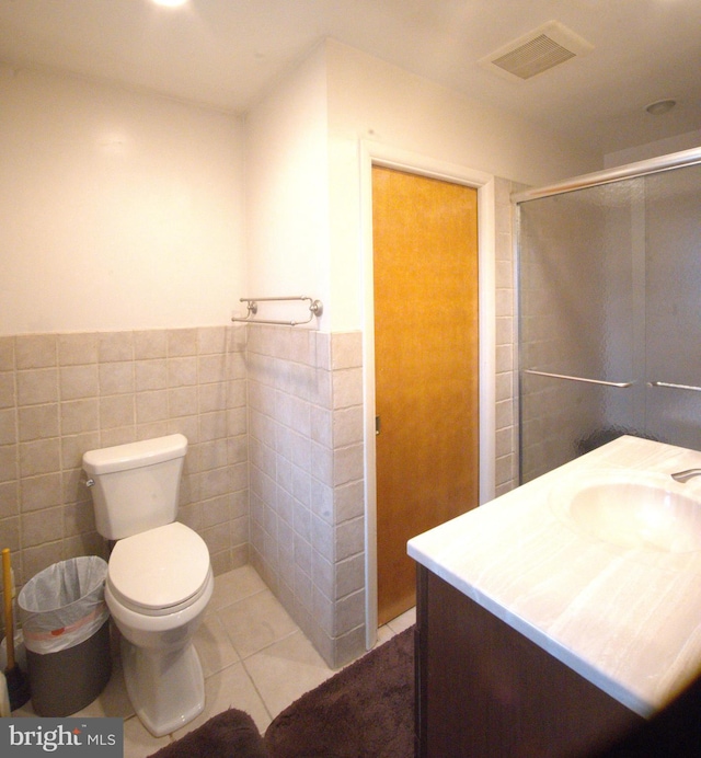 bathroom featuring visible vents, a shower stall, tile walls, toilet, and tile patterned floors