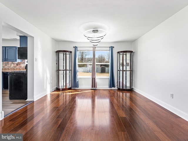 unfurnished dining area with baseboards and wood finished floors