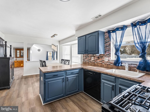 kitchen with visible vents, a sink, blue cabinets, a peninsula, and black appliances