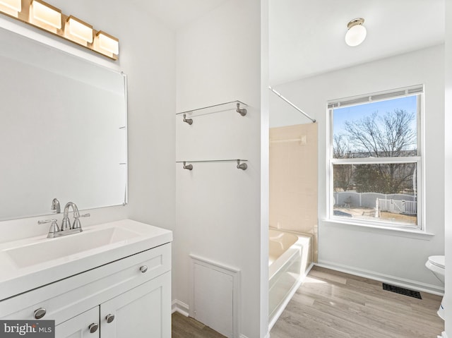 bathroom featuring visible vents, toilet, vanity, wood finished floors, and baseboards