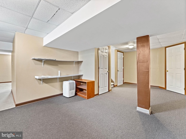 finished below grade area with a paneled ceiling, carpet flooring, and baseboards