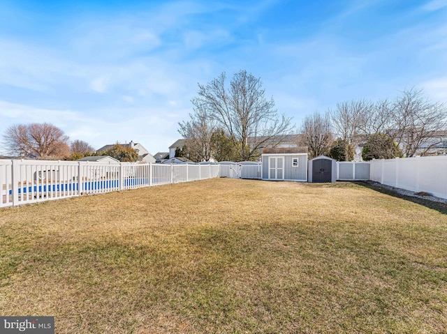 view of yard featuring a shed, a pool, a fenced backyard, and an outdoor structure