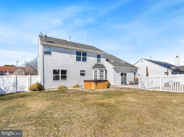 rear view of house with a patio, a lawn, a fenced backyard, and a hot tub