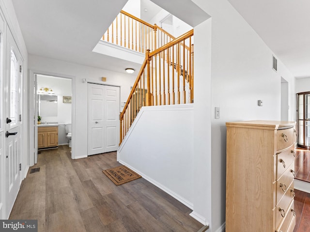 staircase with wood finished floors, visible vents, and baseboards