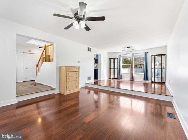 interior space featuring baseboards, visible vents, ceiling fan, and wood finished floors