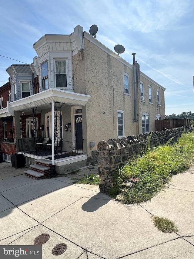 view of side of home with a porch and stucco siding