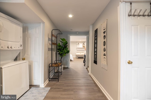 hall with wood finished floors, recessed lighting, baseboards, and stacked washer / drying machine