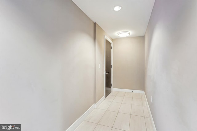 hall featuring light tile patterned flooring and baseboards