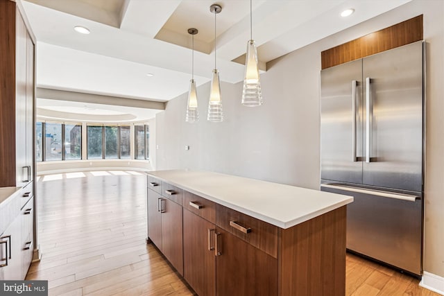 kitchen with light wood-style floors, open floor plan, light countertops, stainless steel built in refrigerator, and decorative light fixtures