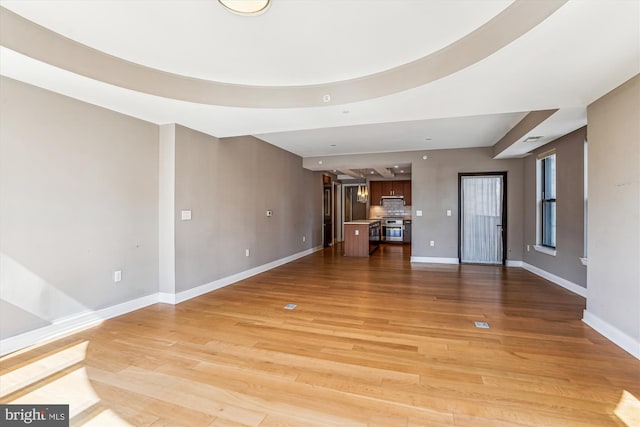 unfurnished living room with light wood-type flooring and baseboards