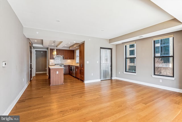 kitchen with light wood-style floors, open floor plan, light countertops, backsplash, and a center island