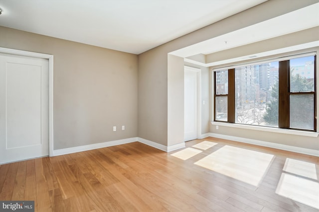 empty room with light wood-type flooring and baseboards